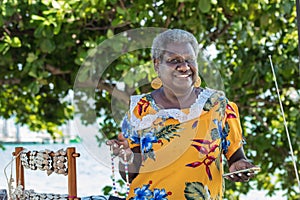 Portrait of a melanesian - australian artisan mature woman smiling, outdoors. photo