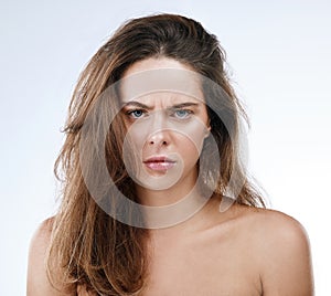 Portrait, messy hair and frown with an frustrated woman in studio on a white background for beauty. Damage, split ends