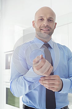 Portrait of mid adult businessman buttoning sleeve at home