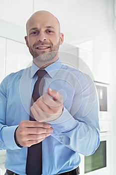 Portrait of mid adult businessman buttoning sleeve at home