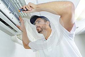 Portrait mid-adult male technician repairing air conditioner