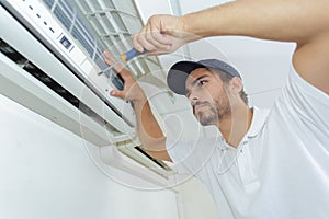 Portrait mid-adult male technician repairing air conditioner