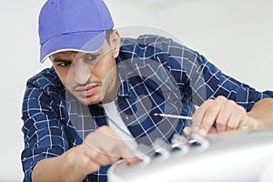 portrait mid-adult male technician repairing air conditioner