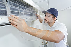 Portrait mid-adult male technician repairing air conditioner