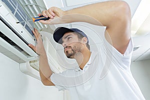 Portrait mid-adult male technician repairing air conditioner