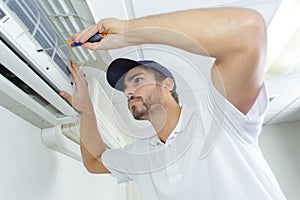 Portrait mid-adult male technician repairing air conditioner