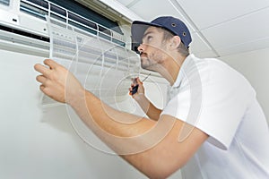 Portrait mid-adult male technician repairing air conditioner