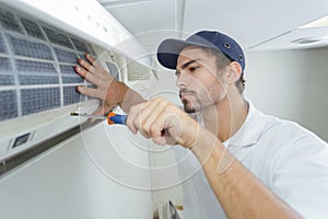 Portrait mid-adult male technician repairing air conditioner