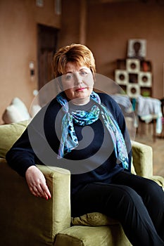 Portrait of mid-adult woman looking at camera sitting in armchair