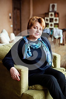 Portrait of mid-adult woman looking at camera sitting in armchair