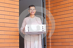 Portrait of mid adult woman with pizza boxes at entrance