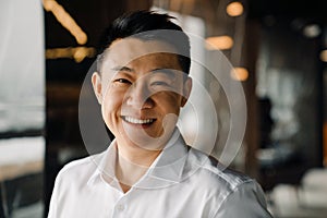 Portrait of midaged smiling asian businessperson in shirt looking straight