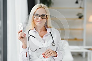 Portrait of middle age female doctor is wearing a white doctor& x27;s coat with a stethoscope around her neck. Smiling