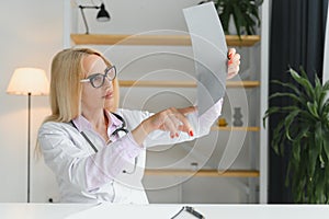 Portrait of middle age female doctor is wearing a white doctor& x27;s coat with a stethoscope around her neck. Smiling