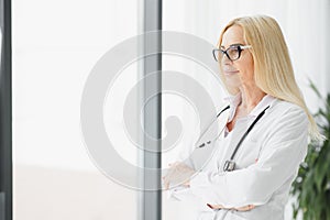 Portrait of middle age female doctor is wearing a white doctor& x27;s coat with a stethoscope around her neck. Smiling