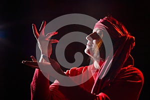 Portrait of middle age woman in red sweater and the turban of wizard or sorcerer on black background. Actress in a magical,