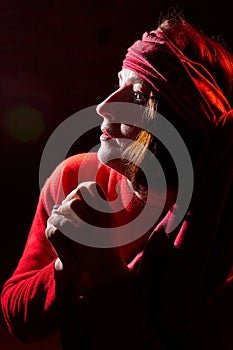 Portrait of middle age woman in red sweater and the turban of wizard or sorcerer on black background. Actress in a magical,