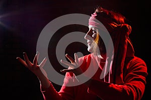 Portrait of middle age woman in red sweater and the turban of wizard or sorcerer on black background. Actress in a magical,