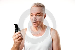 Portrait of middle aged, 45s man holding jar of skin care hand cream, lotion against white studio background.