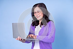 Portrait of middle aged Asian woman using laptop on blue background