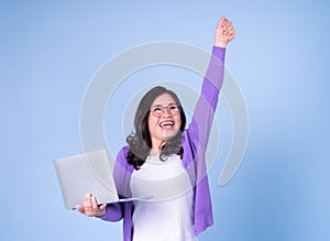 Portrait of middle aged Asian woman using laptop on blue background