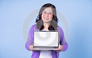 Portrait of middle aged Asian woman using laptop on blue background