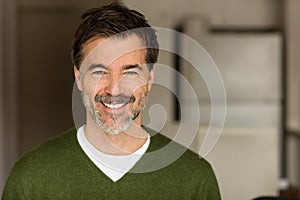 A portrait of a middle-aged bearded man smiling at the camera on a blur background