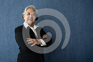 Portrait of middle aged business woman standing isolated on blue background and folded arms looking at the camera with a smile,