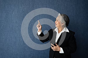 Portrait of middle aged business woman standing isolated on blue background and posing finger pointing and touching, looking at
