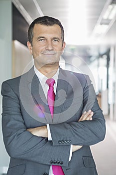 Portrait of middle-aged businessman standing with arms crossed in office