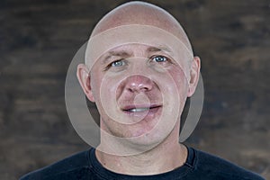 Portrait of middle-aged caucasian bald man looking straight at camera, close up