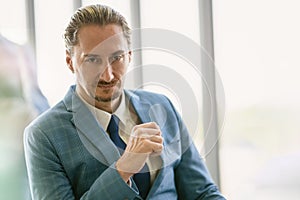 Portrait of middle-aged Caucasian businessman sitting at the office looking toward camera with serious pensive expression in