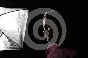 Portrait of a middle aged caucasian man's profile in shadow against a black background.