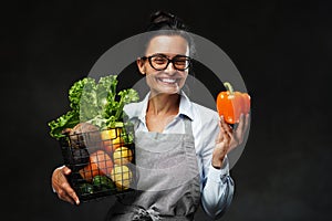 Portrait of a middle-aged female farmer in apron holds a basket of fresh vegetables and fruit