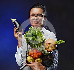 Portrait of a middle-aged female farmer in apron holds a basket of fresh vegetables and fruit