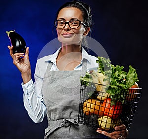 Portrait of a middle-aged female farmer in apron holds a basket of fresh vegetables and fruit