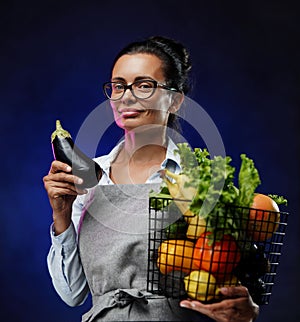 Portrait of a middle-aged female farmer in apron holds a basket of fresh vegetables and fruit