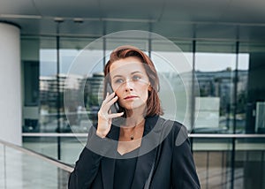 Portrait of a middle-aged female with ginger hair talking on her mobile phone