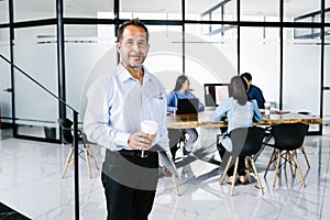 Portrait of middle-aged latin man holding glass of coffee and laptop at business meeting in Latin America