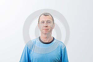 Portrait of a middle-aged man against a white wall background looking to camera. Serious expresion of  mature man with serious