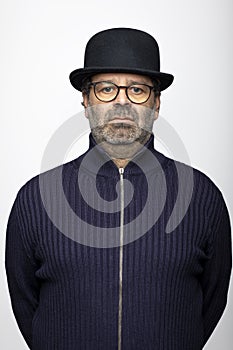 Portrait middle aged man with glasses, bowler hat and round glasses. He is wearing a dark jumper