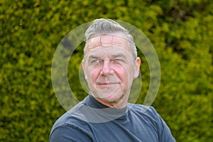 Portrait of a middle-aged man with gray hair standing in the garden