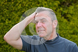 Portrait of a middle-aged man with gray hair standing in the garden