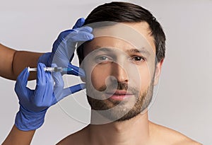 Portrait Of Middle-Aged Man Receiving Wrinkle-Removing Injection, White Background