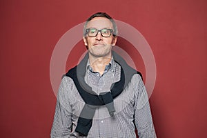 Portrait of middle aged man wearing glasses on red background