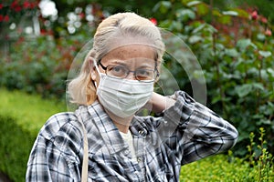Portrait of middle aged mixed race blonde woman with eyeglasses wearing white surgical mask