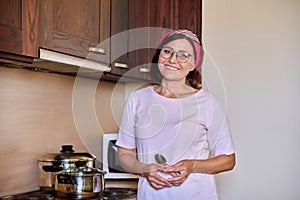 Portrait of a middle aged smiling woman preparing food in the kitchen