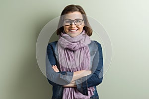 Portrait middle aged woman with crossed arms. Background green wall.