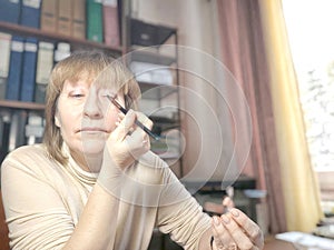 Portrait of a middle-aged woman doing eye makeup. Selfie portrait of a lady who is businesswoman, accountant, manager