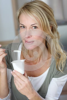 Portrait of middle aged woman eating yoghurt